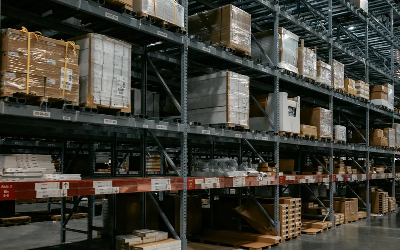 Warehouse storage racks beneath an illuminated high ceiling.