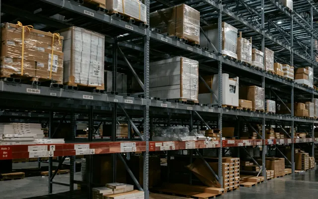 Warehouse storage racks beneath an illuminated high ceiling.